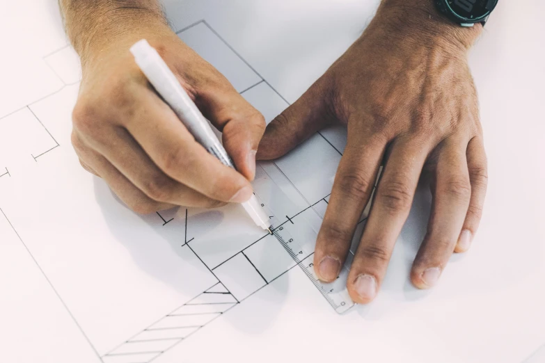 the hands of a man who is holding a pen over a blueprint