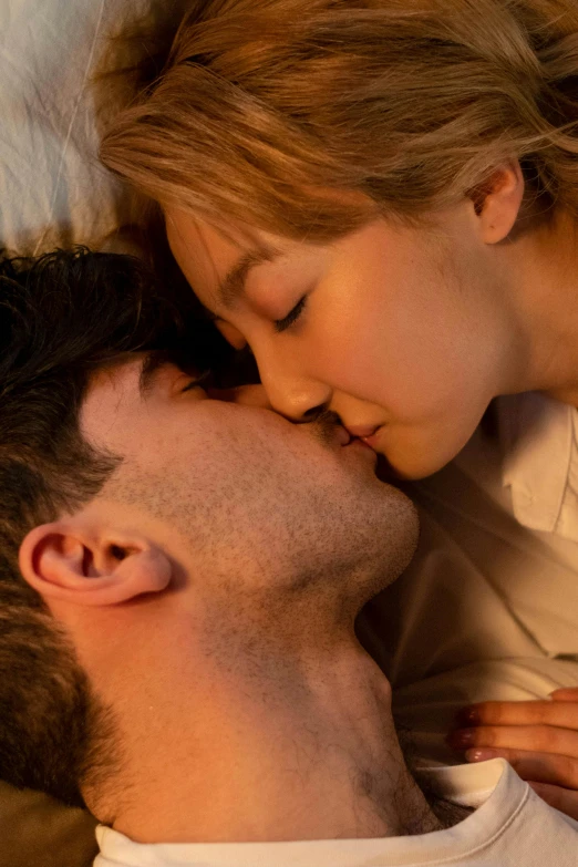 a young couple is sharing a kiss while lying in bed