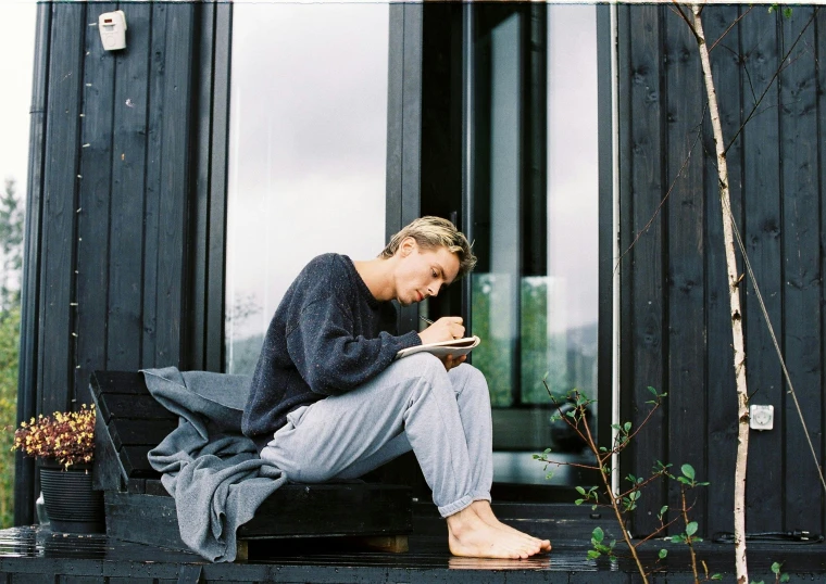 a woman sitting on the porch holding a tablet