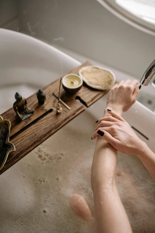 a woman's hands in the bathtub being held under a faucet