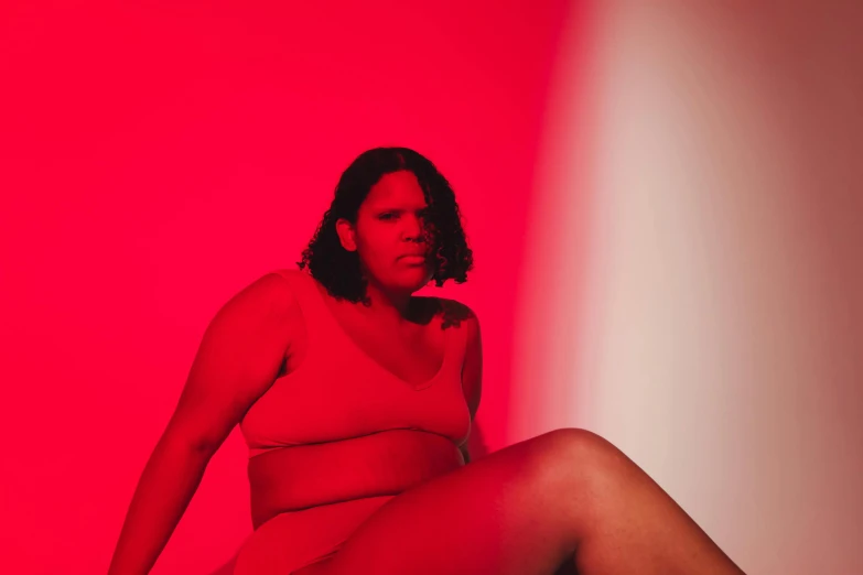 a woman in a red dress is sitting on a stool