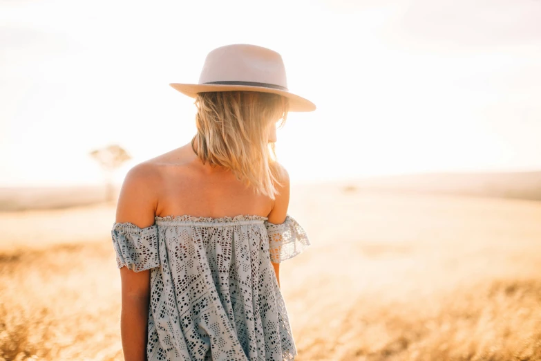 a woman standing in a field in a sun hat
