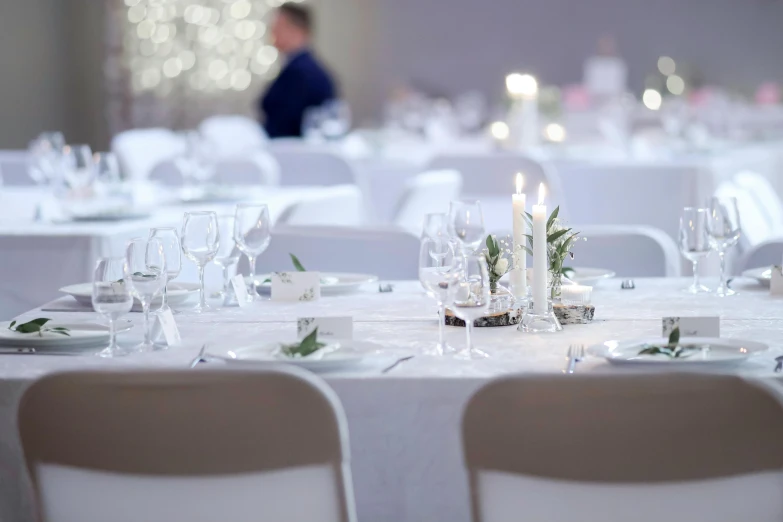 several white dining tables and chairs decorated with candles