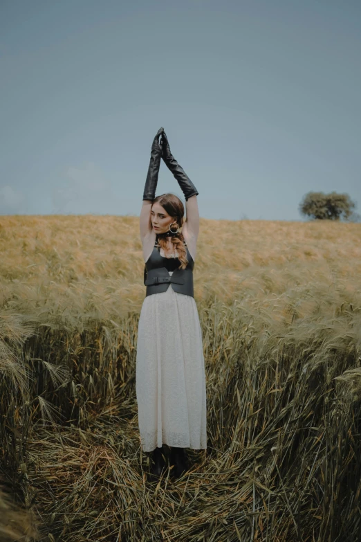 a woman in a field holding a camera up to her head