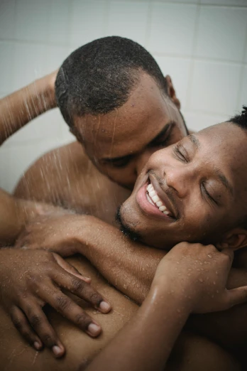 two males smiling and rubbing their faces under the shower heads