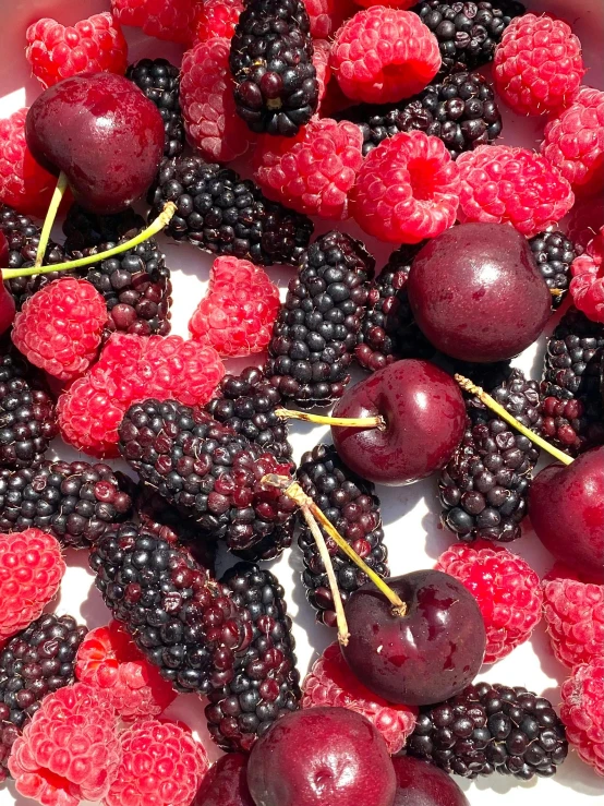 there are many red berries and blackberries in a white container