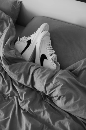 white sneakers are covered by a gray blanket