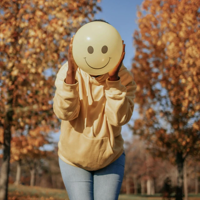 a woman wearing an oversized smile balloon covering her face