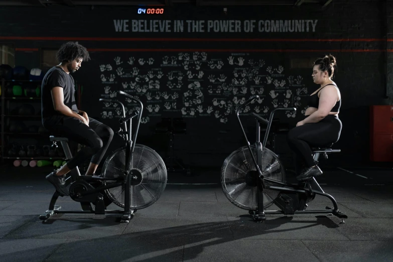 two people sit in gym equipment with the word we believe in the power of community