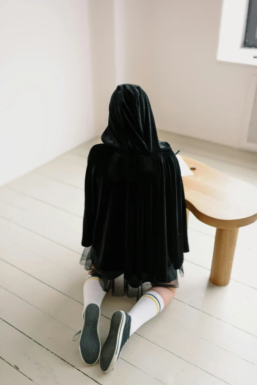 child sitting on the floor with her face covered in a blanket