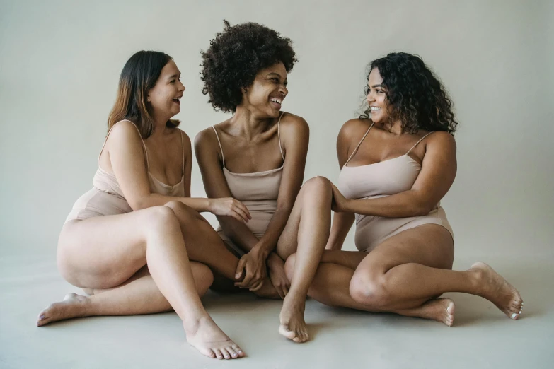 three young women sitting on the floor laughing and posing