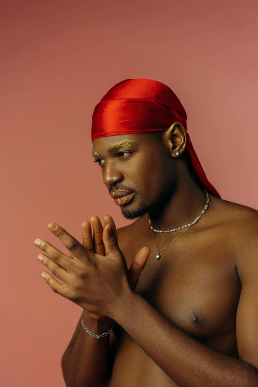 shirtless man in red headdress and gold jewelry