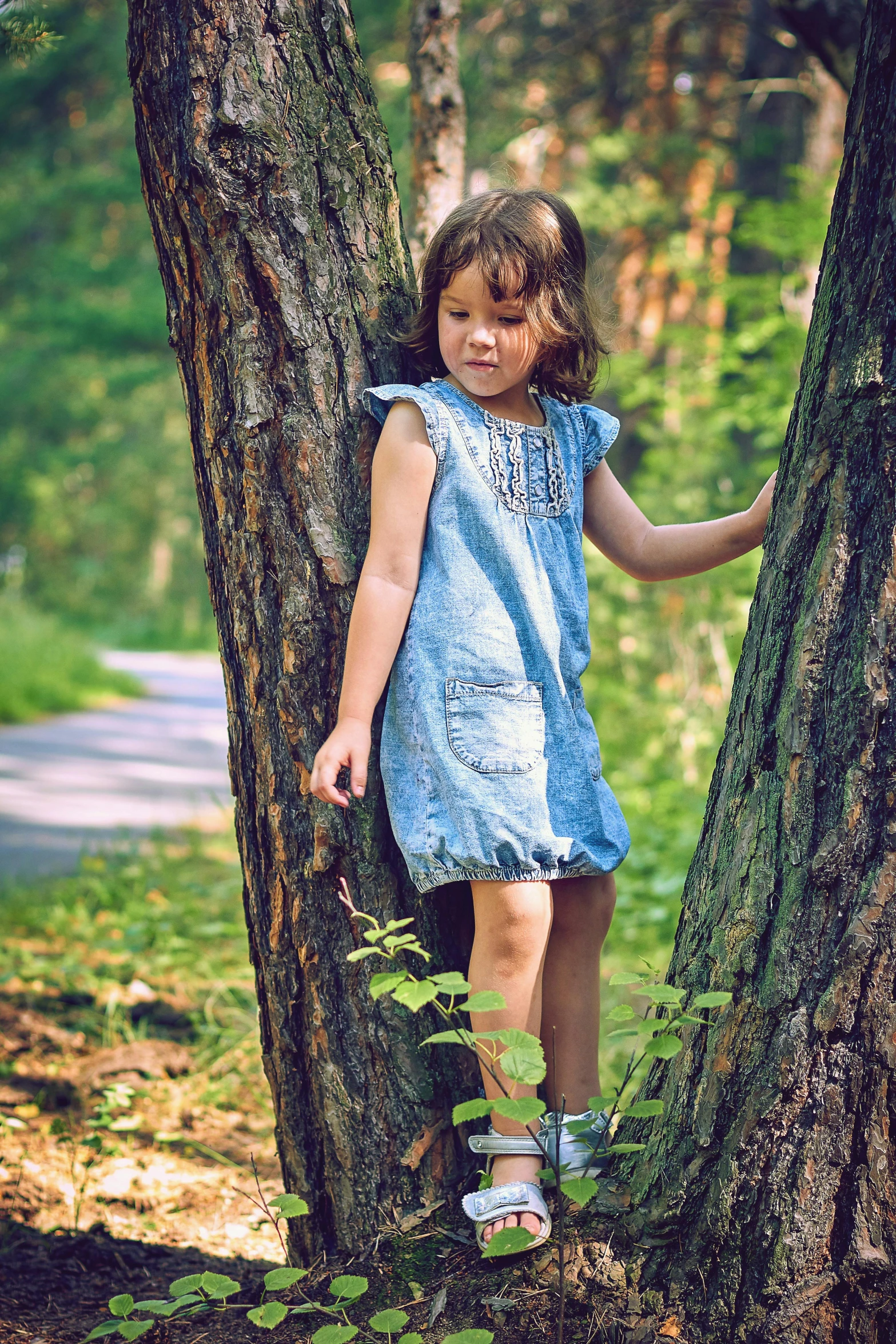 a  poses for a po while standing up against a tree in a wooded area