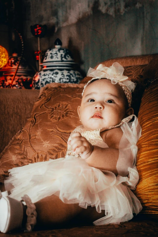 an adorable little girl sitting on a couch holding onto a blanket