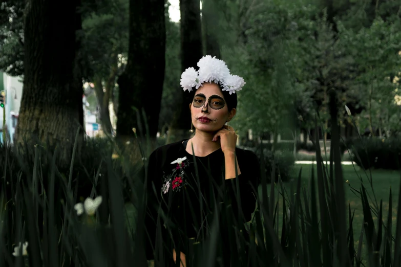 a woman stands in grass with headgear around her face