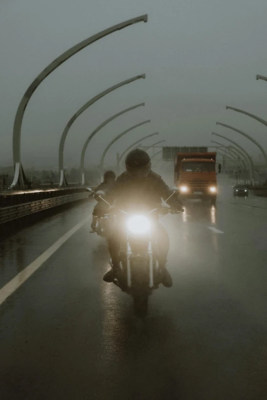 people riding down the highway in their motorcycle on a foggy day