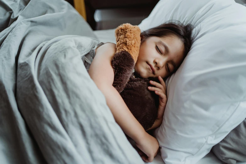 a little girl sleeping in her bed with a teddy bear