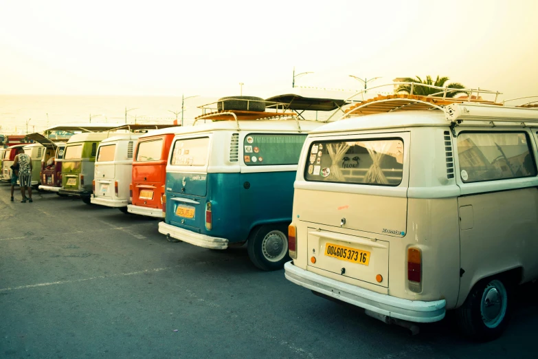 several vans are lined up with surfboards on their top