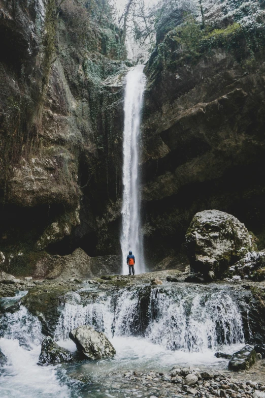 two people standing in front of a waterfall