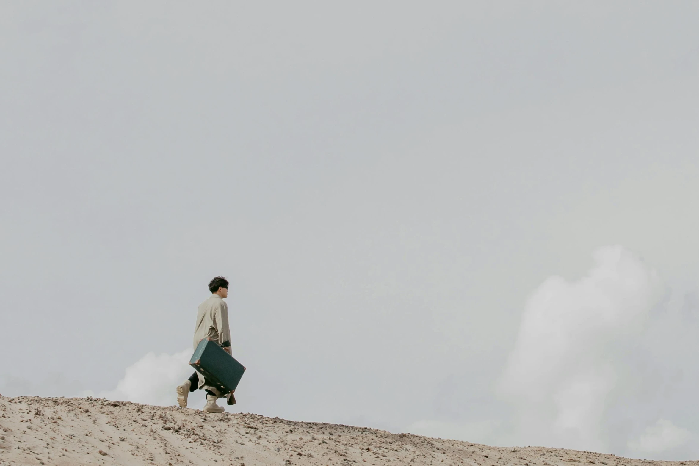 a woman walking up the side of a sand hill