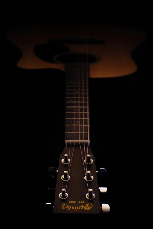 a guitar with its neck illuminated from the spot