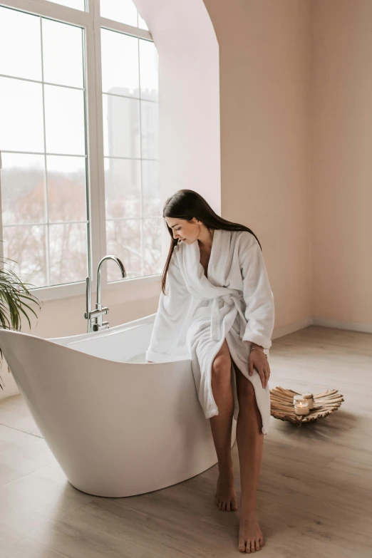a woman in a white robe sitting in a bath tub