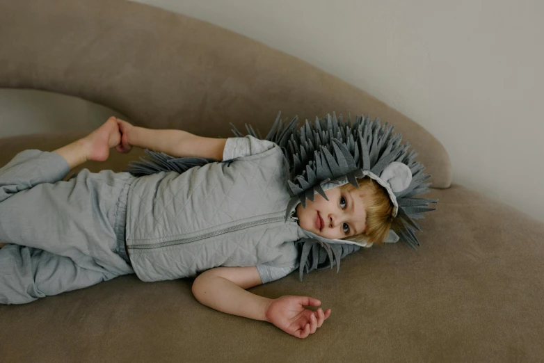 a little boy wearing a spikes headpiece on top of a couch