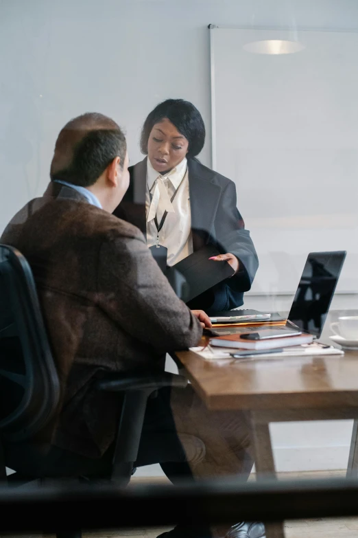 two people sitting around a conference table with laptop computers