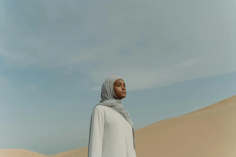 an image of woman wearing white outfit walking in desert