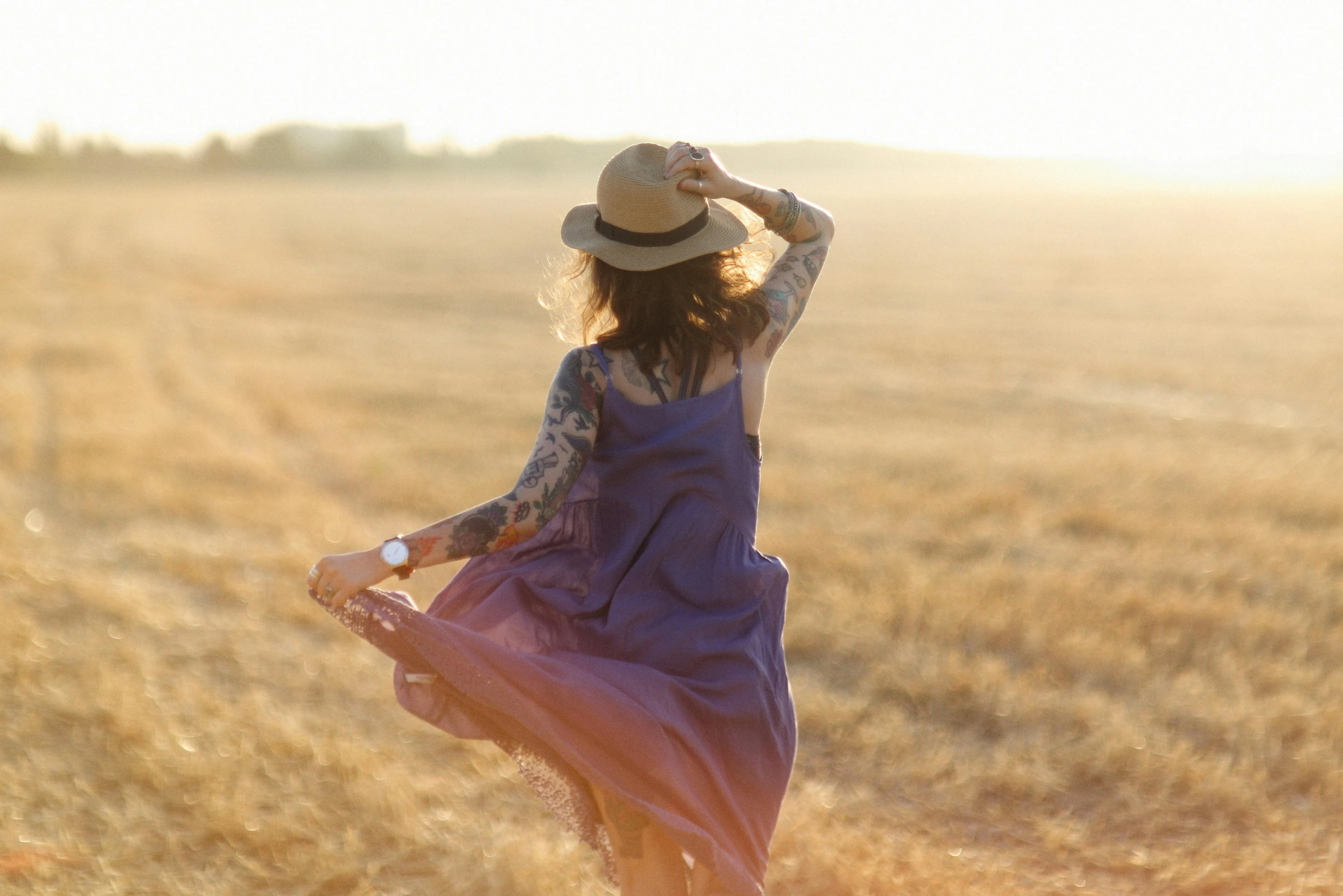 a woman standing in a field with a hat on