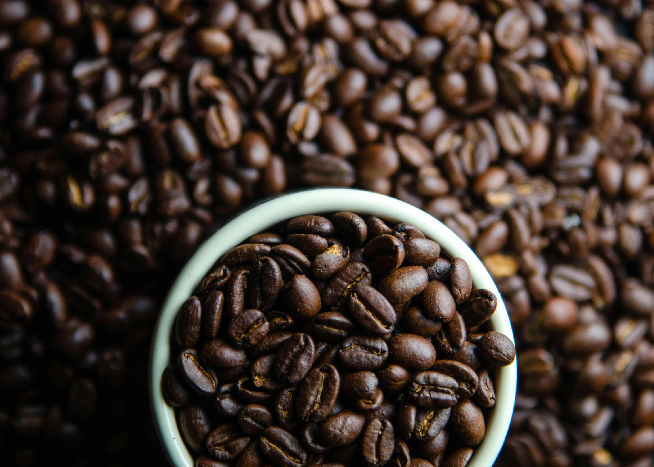 a white ceramic cup with roasted coffee beans on it