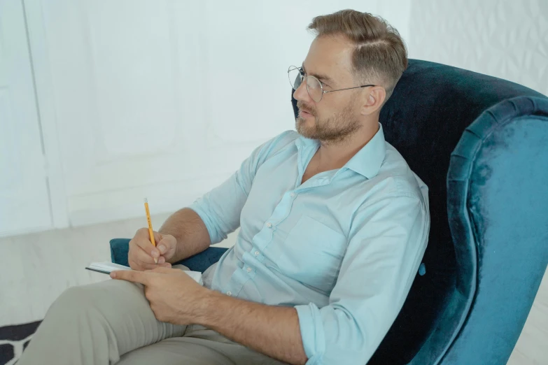 a man sitting in a chair is holding his pen