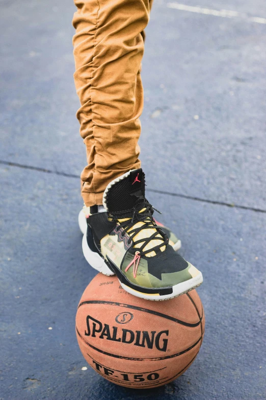 a person wearing black and yellow sneakers stands next to a basketball