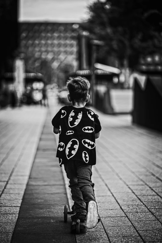 a small  riding a skateboard down the sidewalk