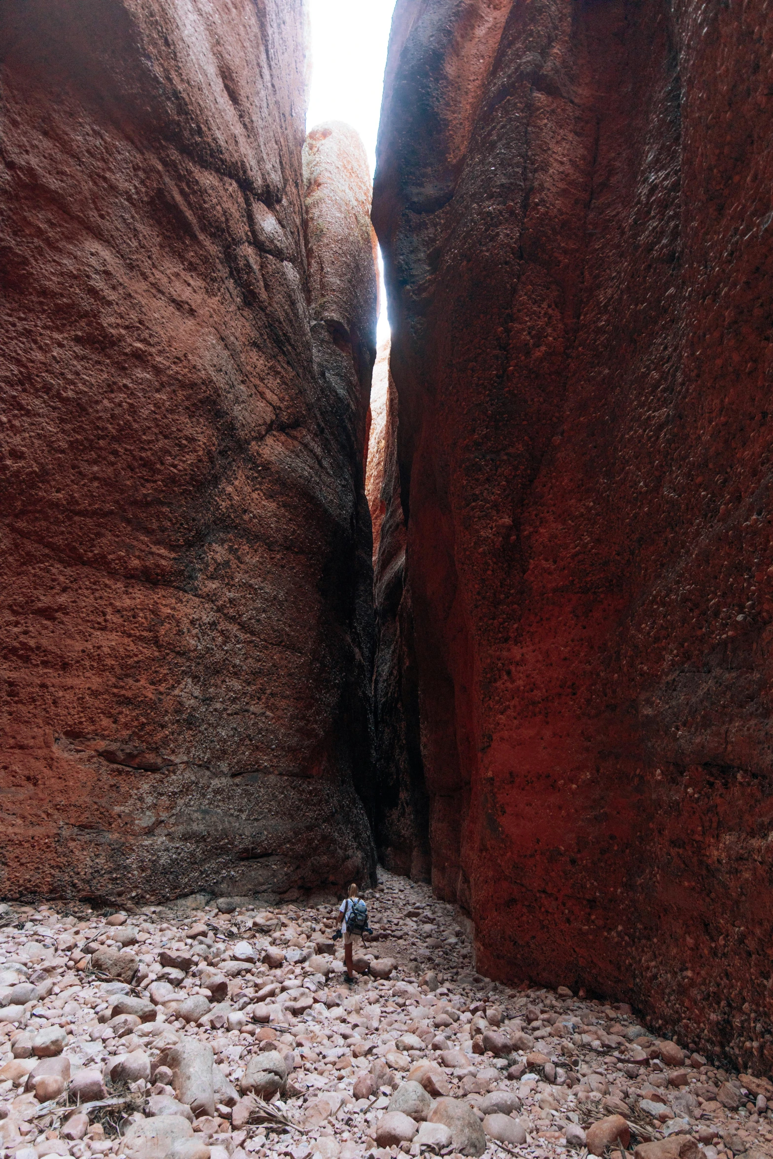 a lone person walking between two very narrow rocks