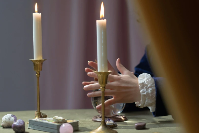 a person lighting a candle in front of a table