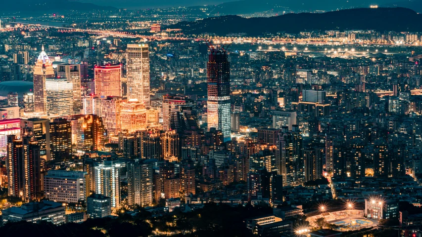 a city skyline in night from the top of a hill