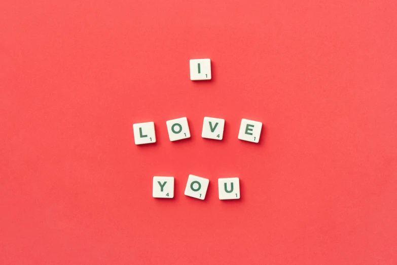 scrabble letters spelling out i love you on red paper