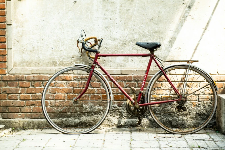 a red bike is parked against a white wall