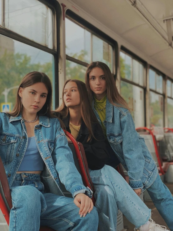 three girls sitting on seats next to a building