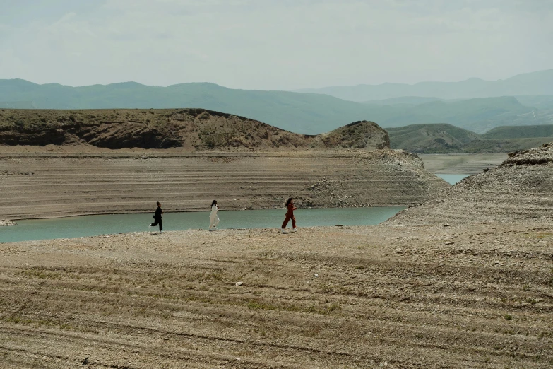 two people walk on the beach above a lake