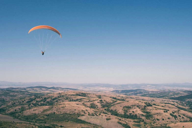 someone flying on a parachute over the mountains