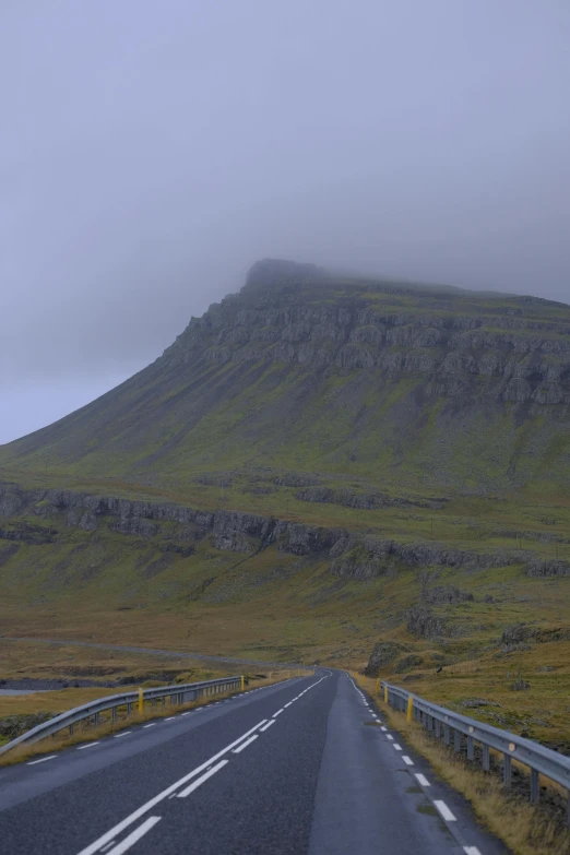 a bus driving along a highway under a foggy mountain