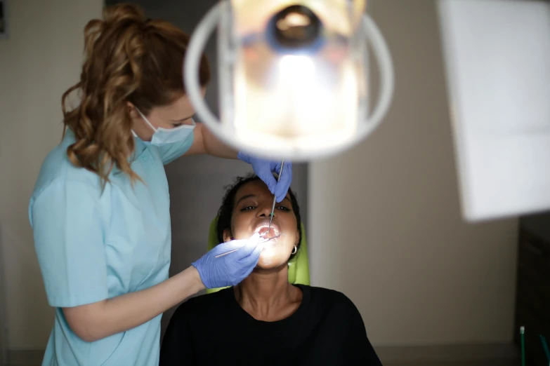 a woman being given the dental hygiene of her teeth