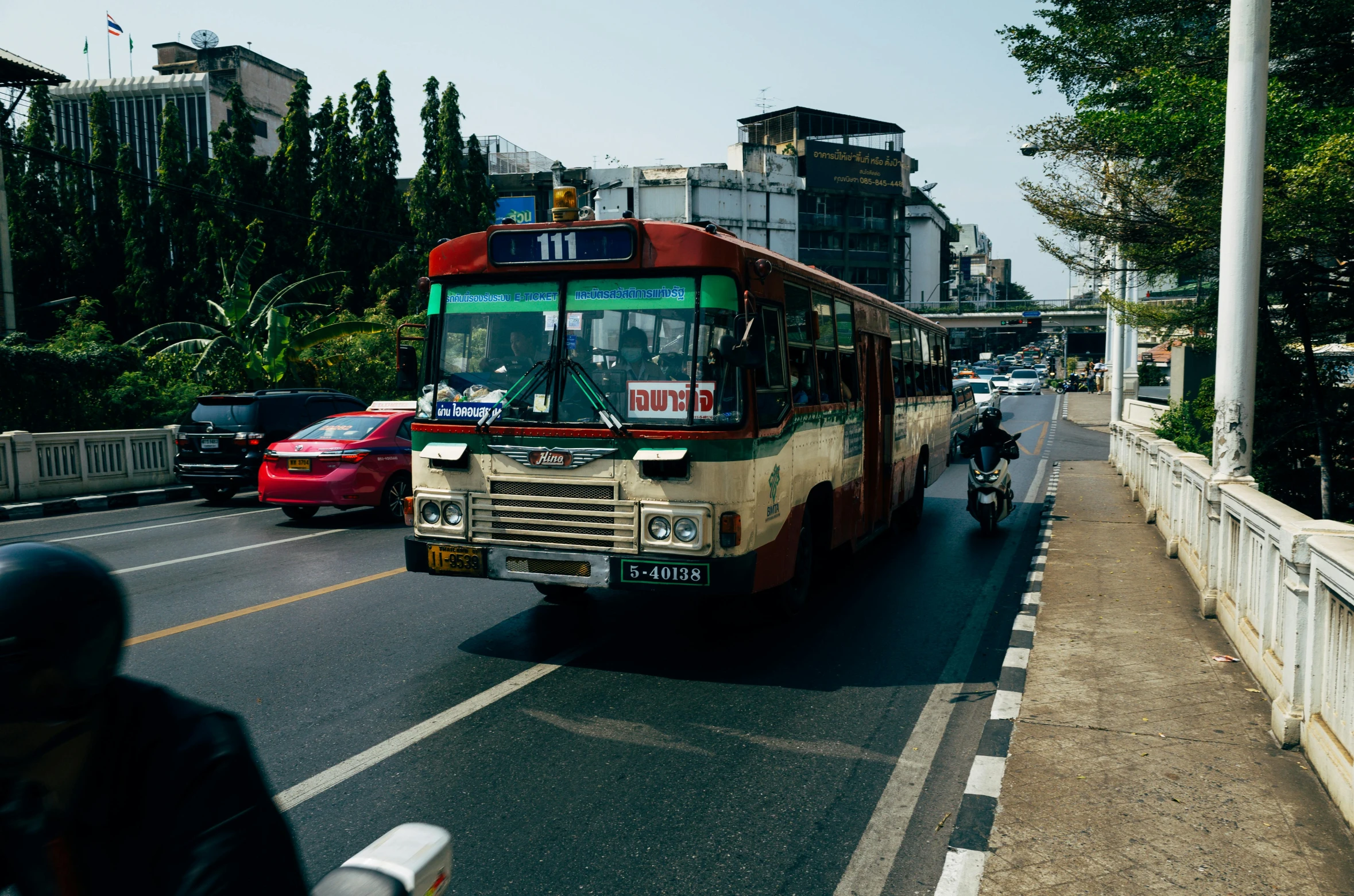 red bus coming down a road near a crowd