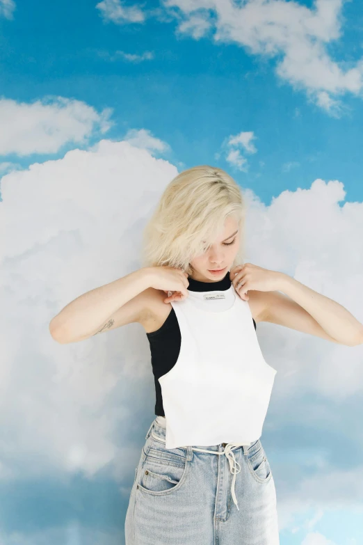 a woman in a white top posing on a cloud background