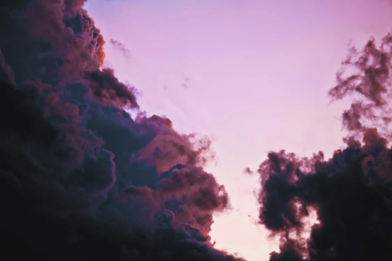 clouds are silhouetted against a purple sky