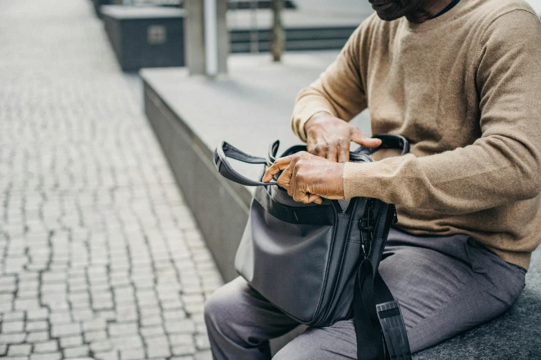 a man on a bench holds his hand in a bag