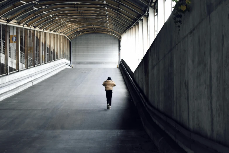 a man walking down a corridor in a tunnel