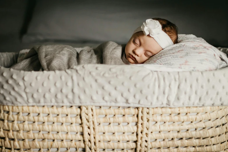 a sleeping newborn girl curled up in a basket